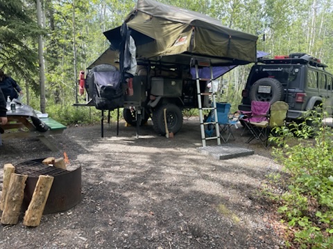 The trailer with the rooftop tent and awning deployed at camp